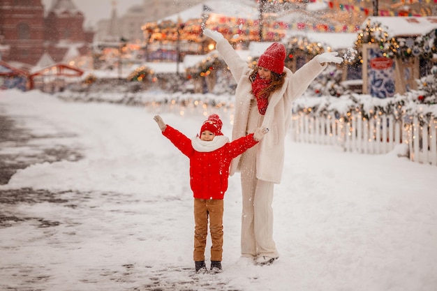 Madre e hijo con ropa de abrigo se divierten en invierno en una feria nevada de Año Nuevo en la Plaza Roja de Moscú