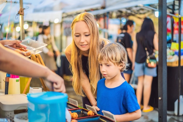 Madre e hijo son turistas en el mercado de comida asiática de Walking Street