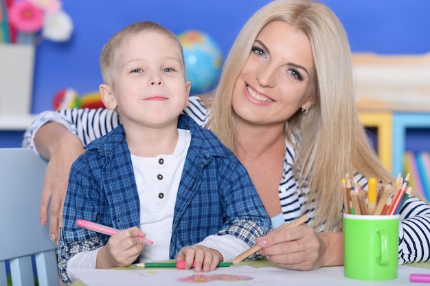 Foto madre e hijo sonrientes dibujando con lápices