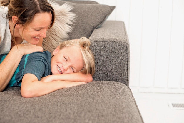 Madre e hijo sonrientes tirados en un sofá