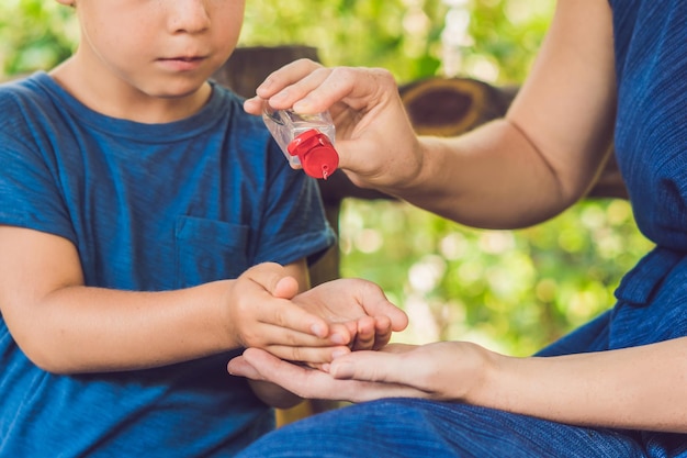 Madre e hijo usando gel desinfectante para manos en el parque antes de un refrigerio