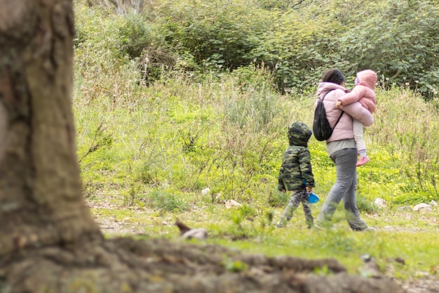 Madre e hijos caminando en el campo irreconocible