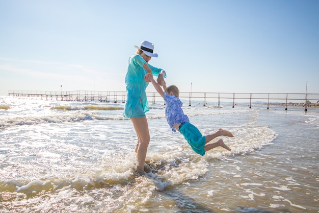 Madre e hijos están jugando en el mar en la playa.