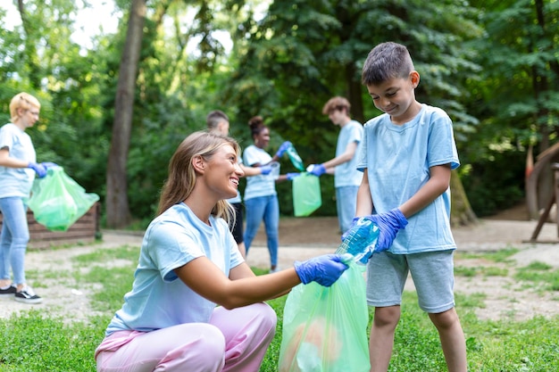 Madre e hijos están recogiendo la basura para limpiar el bosque.