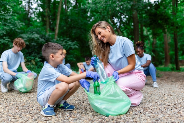 Madre e hijos están recogiendo la basura para limpiar el bosque.