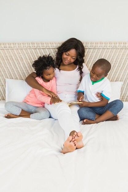 Madre e hijos leyendo en la cama