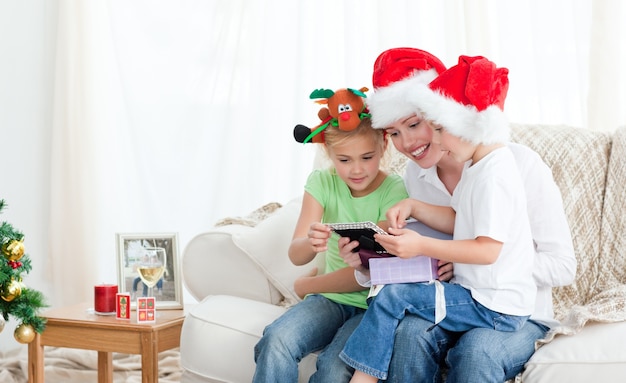 Madre e hijos mirando un calendario sentado en el sofá