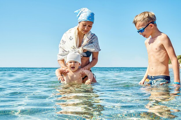 Madre e hijos nadan en aguas cálidas de mar poco profundo en un día soleado