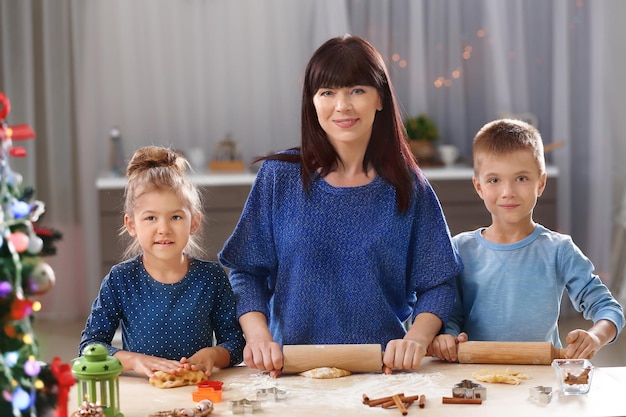 Madre e hijos pequeños haciendo galletas de Navidad en la cocina