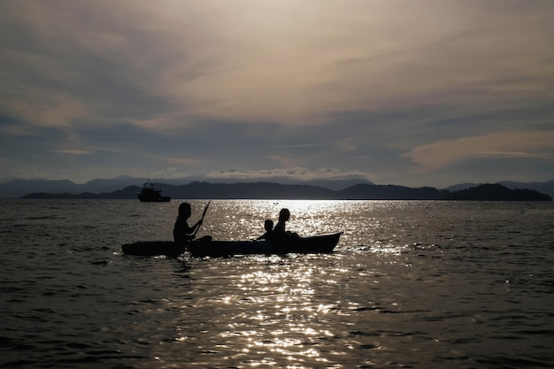 Madre e hijos remando kayak en el mar de vacaciones