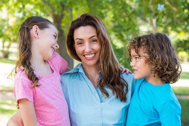 Madre e hijos sonriendo y besándose en un parque