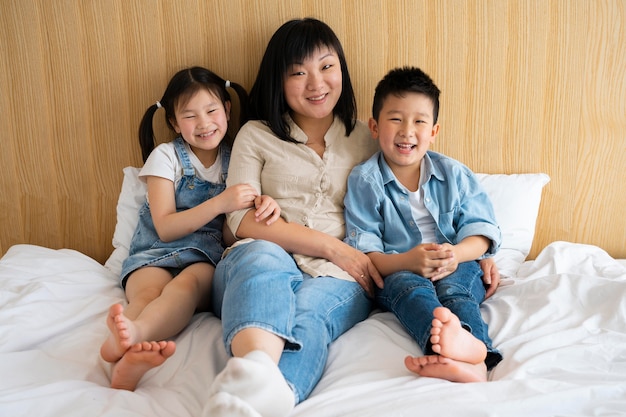 Foto madre e hijos de tiro completo en la cama