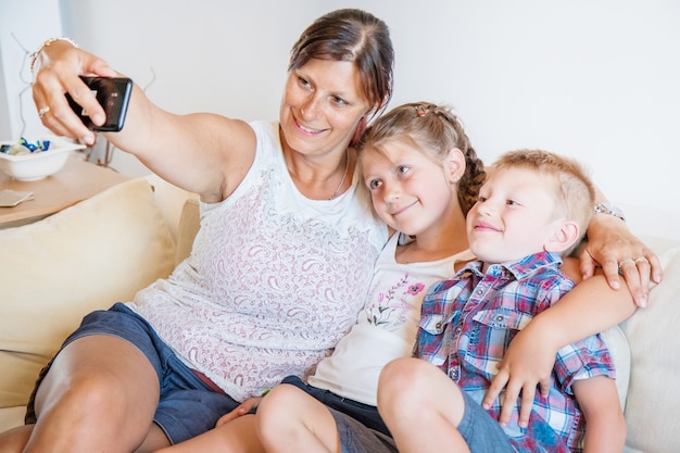 Madre e hijos tomando un selfie en el sofá.Familia feliz