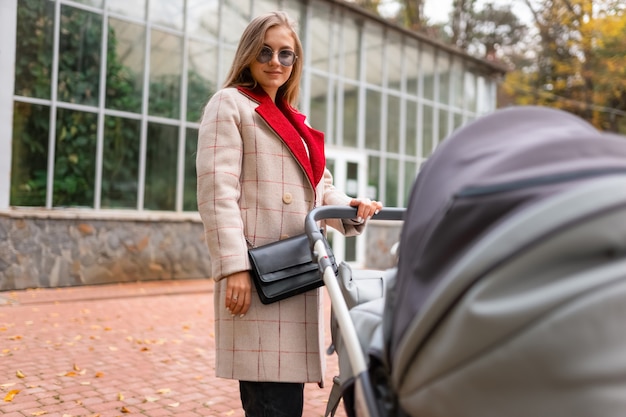 Madre elegante con cochecito de bebé para pasear