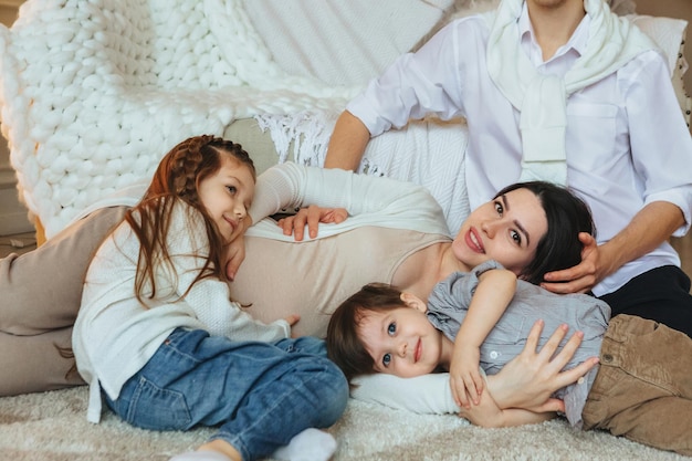 Foto madre embarazada con hijos tendidos en la cama en casa