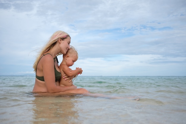 madre embarazada con pequeña hija en la playa