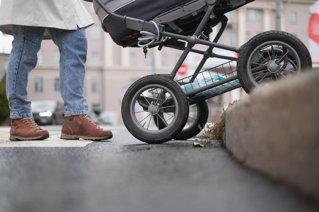 Madre empujando cochecito de bebé en un paso de peatones