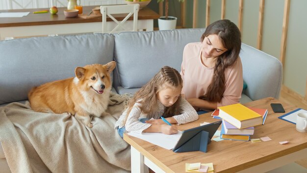 Una madre encantadora ayuda a su hija alegre a hacer los deberes.