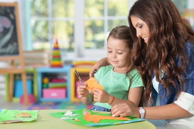 La madre le enseña al niño a hacer artículos artesanales