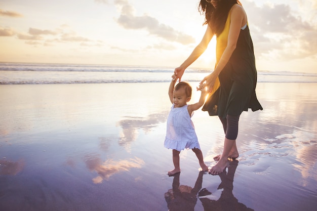 Madre enseña a su hija a caminar por la playa