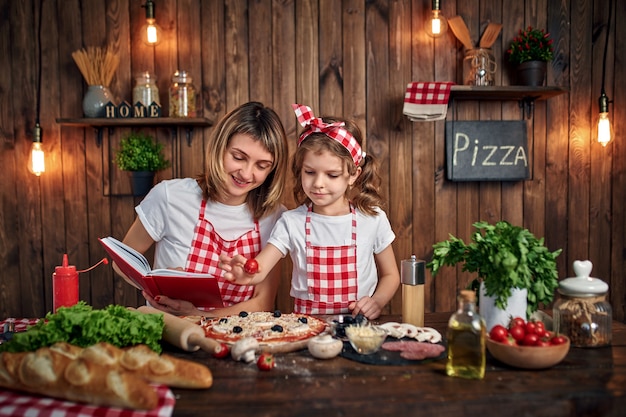 Madre enseñando a hija cocinando pizza