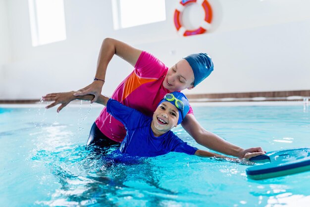 Madre enseñando a nadar a su hijo en la piscina