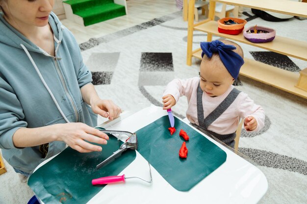 Madre enseñando a niño pequeño a hacer formas con PlayDoh