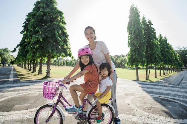 Madre enseñando a su hija a andar en bicicleta en el parque