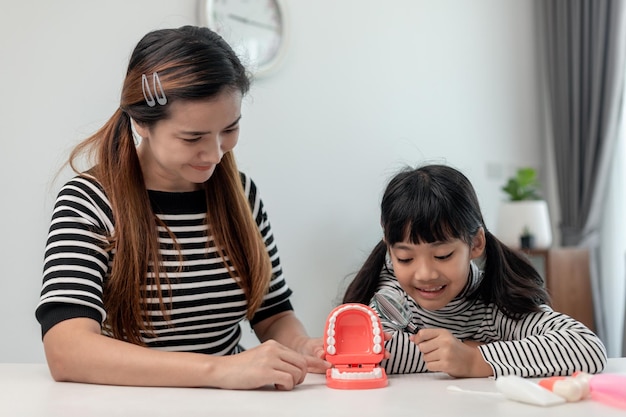 Madre enseñando a su hija a cepillarse los dientes en casa