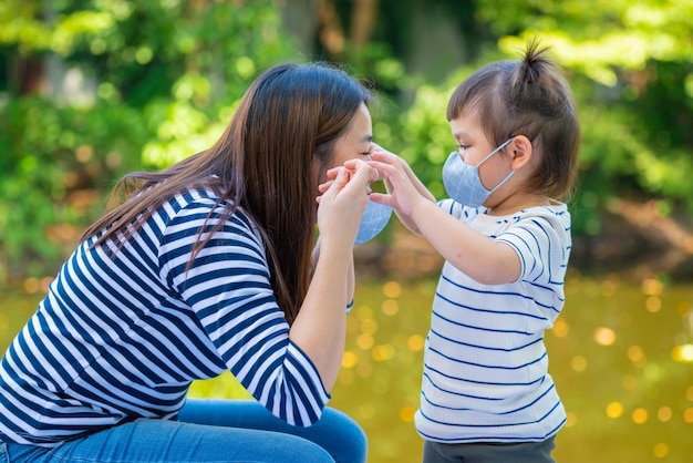 Madre enseñando a su hija a ponerse una marca facial protectora antes de salir al aire libre