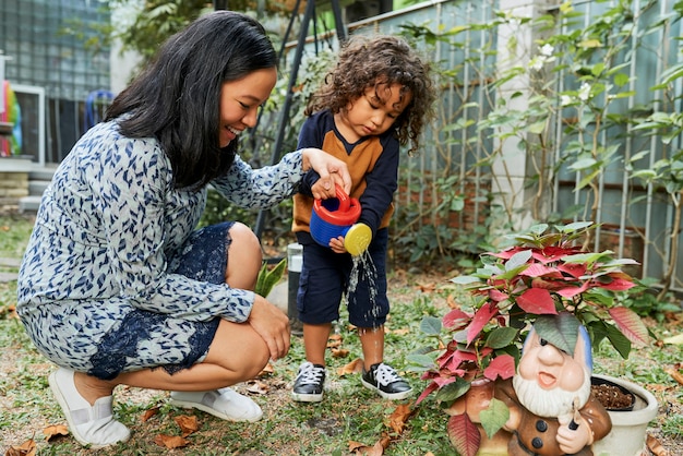 Madre enseñando a su hijo a regar las plantas