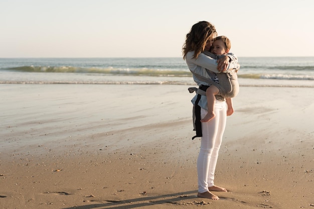 Foto madre con ergobaby con niño pequeño en la playa