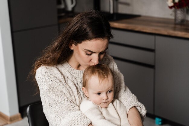 La madre está abrazando y besando a su hija en la cocina Maternity Mon y su hijo pasan tiempo juntos en casa