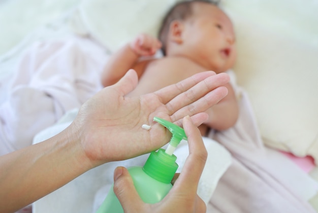 La madre está aplicando una crema de loción en el cuerpo del bebé después del baño. Concepto de cuidado del bebé