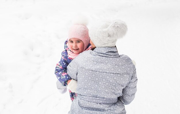 La madre está caminando con su hija en el bosque nevado y abrazándose