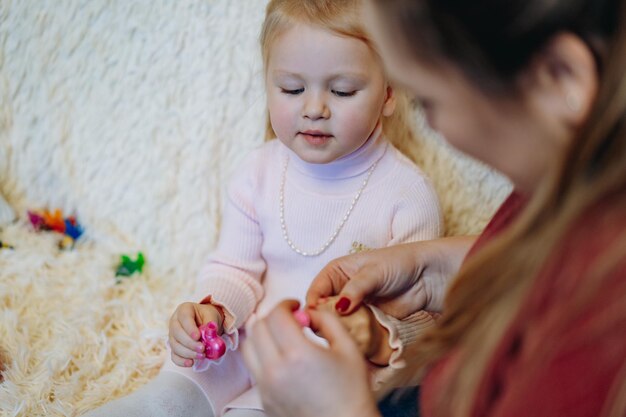 La madre está coloreando las uñas de su niña con esmalte de uñas rosa