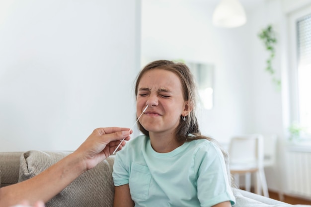 La madre le está haciendo la prueba rápida de covid-19 en casa a su hija enferma en casa. Mamá examina a una niña para detectar una infección por coronavirus y se hace una prueba rápida de COVID-19