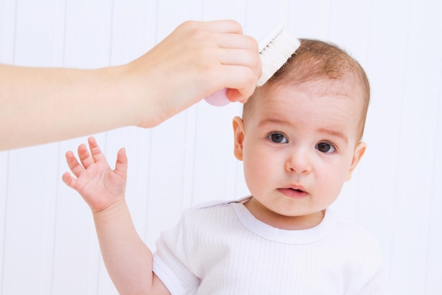 La madre está peinando el cabello hermoso del bebé