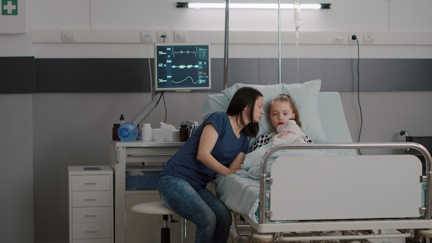 Madre explicando el tratamiento con medicamentos a su hija enferma después de sufrir una cirugía médica