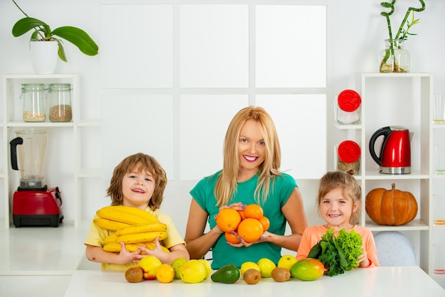 Madre de familia e hijo, hija e hijo, batido mezclado con ingredientes de frutas saludables en la cocina Niños lindos con madre sosteniendo frutas y verduras saludables