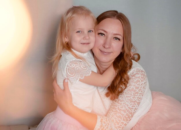 Madre de familia feliz e hija pequeña se abrazan en Navidad.