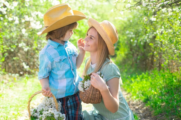 Madre de familia feliz con flores de hijo en picnic Madre de familia con niño sentado en el césped en el parque