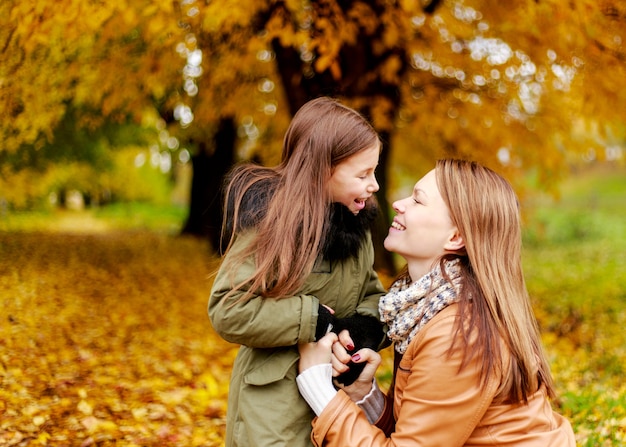 Madre de familia feliz y pequeña hija del niño que juegan en otoño a pie. Familia feliz. Las vacaciones escolares.