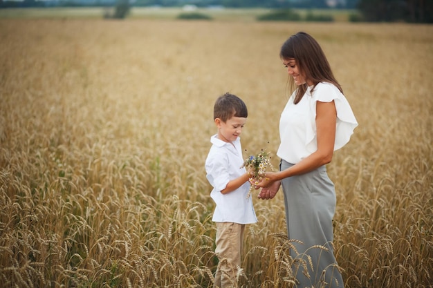 Madre de familia con hijo caminando en el campo sonriendo tomados de la mano