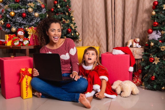 La madre de la familia y la niña usan la computadora portátil en casa durante las vacaciones de Navidad.
