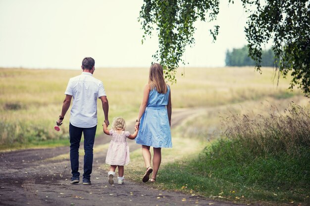 Madre de familia, padre e hija pequeña hermosa y feliz al aire libre en la carretera en el campo