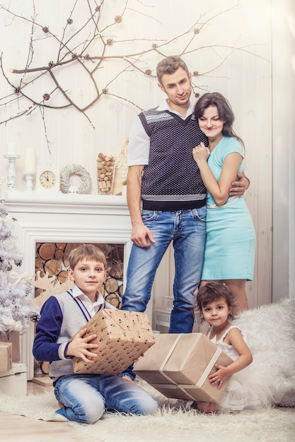 Madre de familia, padre e hijos con regalos en hermosas cajas en el interior de Navidad