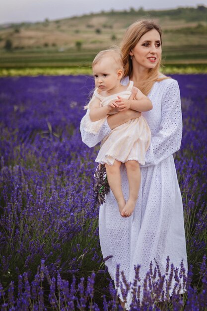 Una madre feliz abraza a su hija y sonríe mientras está de pie en un campo de lavanda