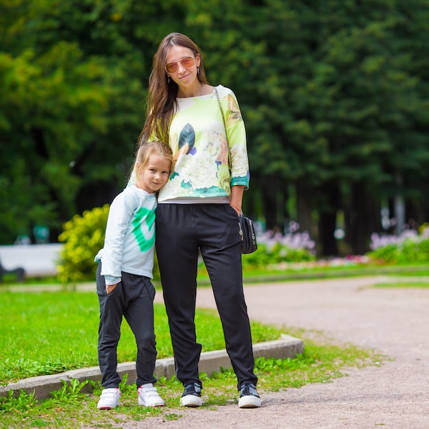 Madre feliz y adorable niña disfrutando del clima cálido en el hermoso parque