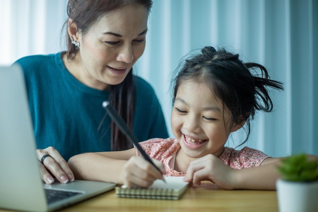Madre feliz ayudando a su linda hija a estudiar en línea en casa Padre e hijo viendo lecciones de arte juntos en la computadora portátil